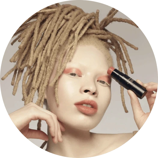 Albino young woman looking into the camera while applying eyeshadow with a makeup stick