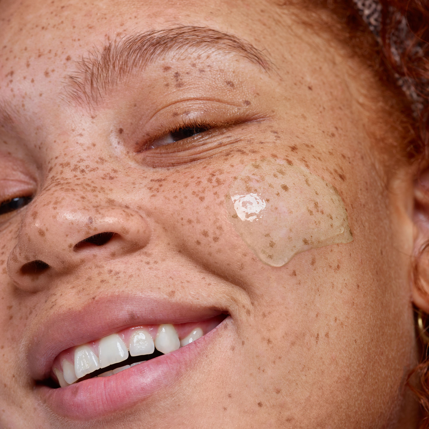 Nudeskin角質除去製品を顔に塗ったそばかすのある若い女性
