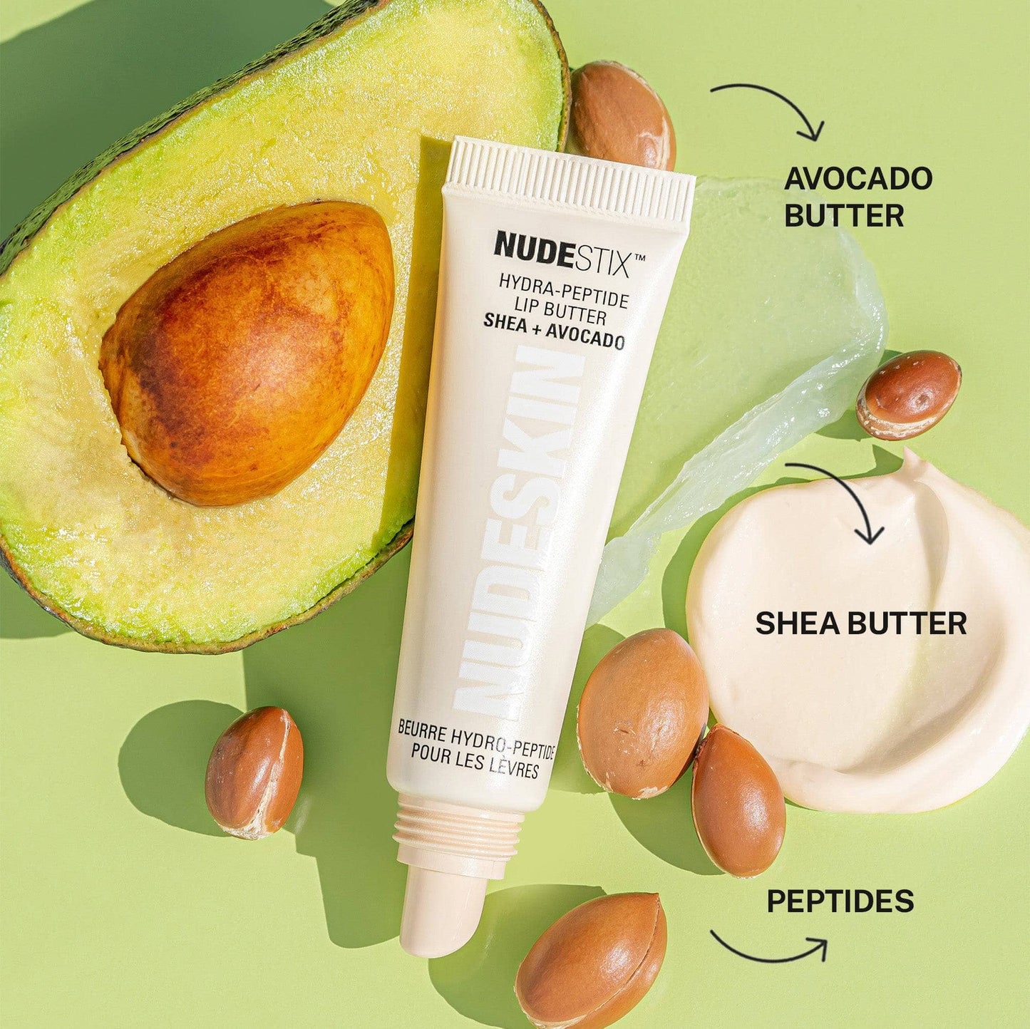 Hydra-Peptide Lip Butter in shade Clear Gloss. Flat lay with avocado and shea butter