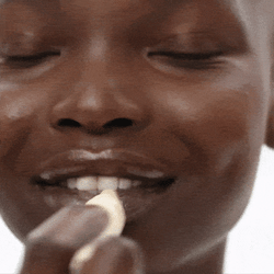 Dark skinned young woman applying Hydra-Peptide Lip Butter in shade Clear Gloss