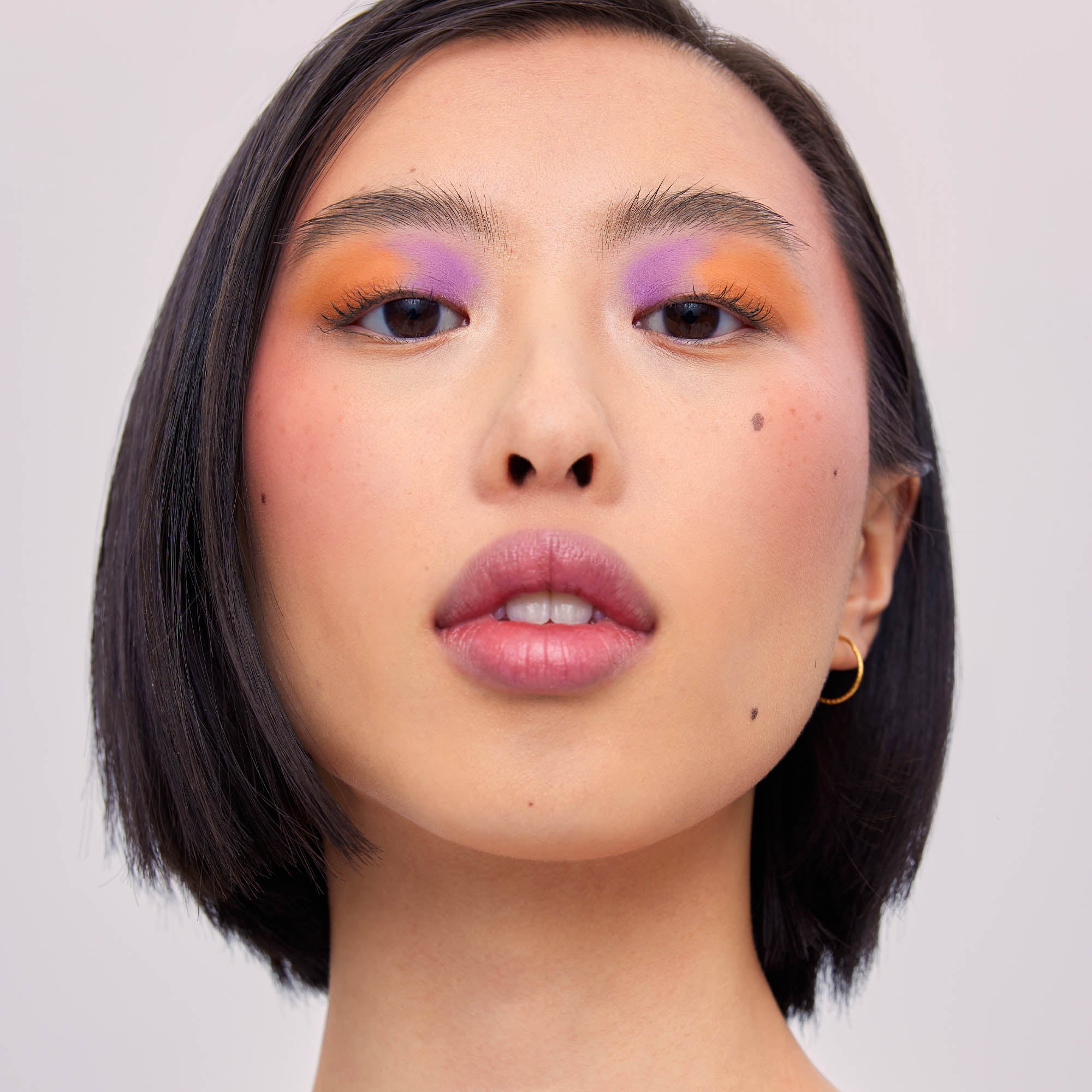 Light skinned Asian young woman with bright purple and orange eyeshadow