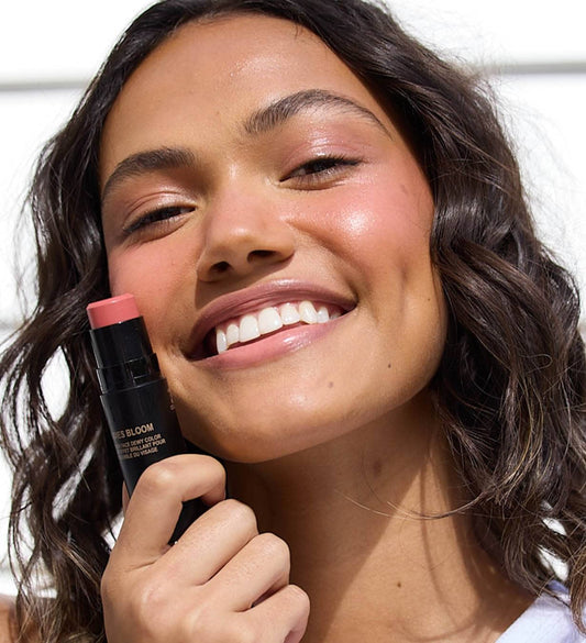 model holding nudies bloom near her right cheek