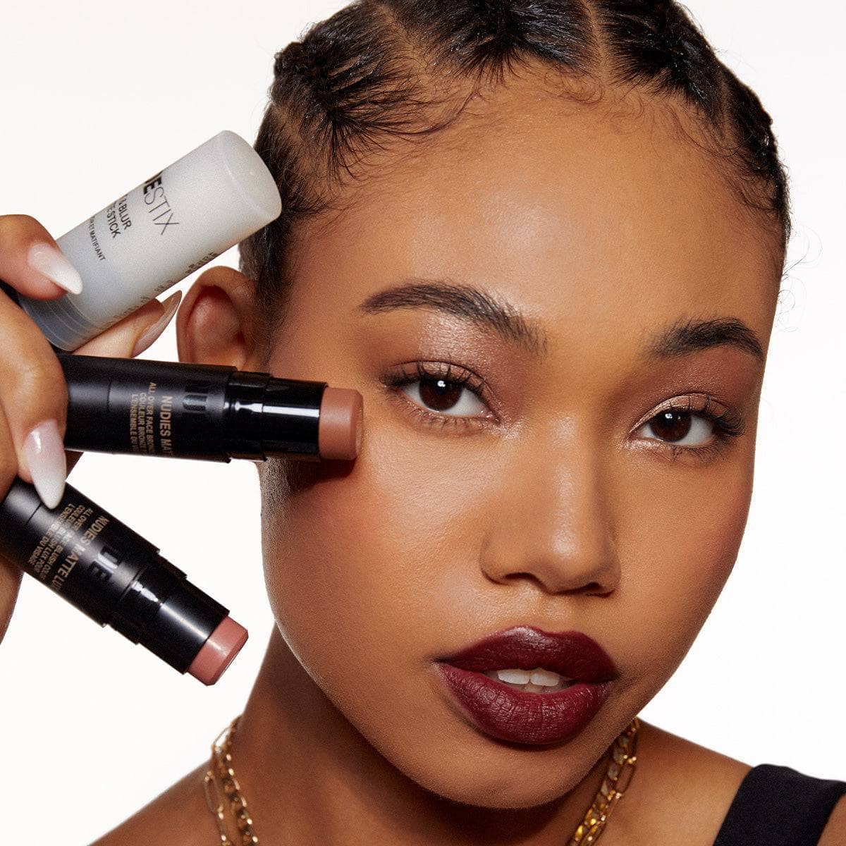 Dark skinned young woman holding No Edit, No Filter, Just Glam sticks