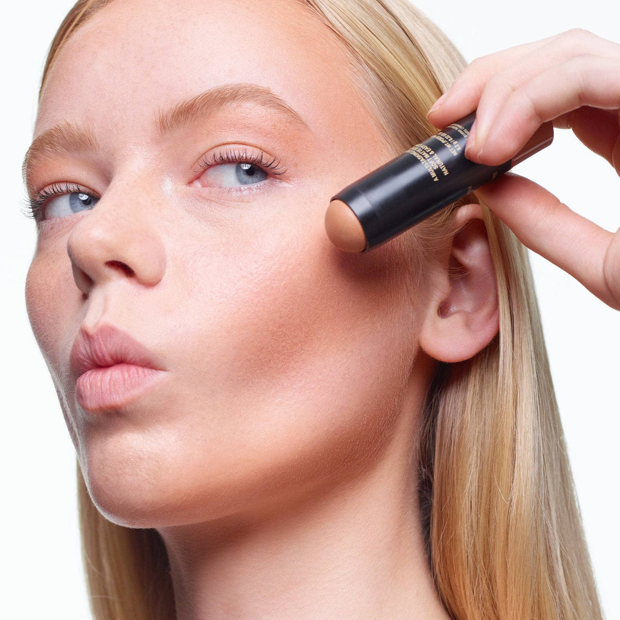 Young woman applying on Tinted Blur Sculpt Stick light