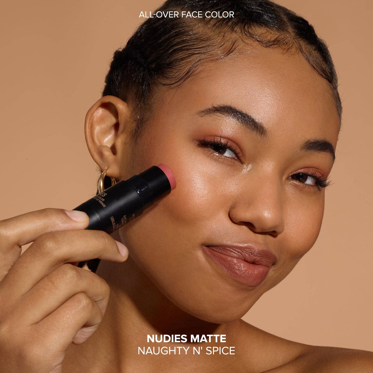 Dark skinned young woman wearing Nudies Matte Blush in shade Naughty N' Spice