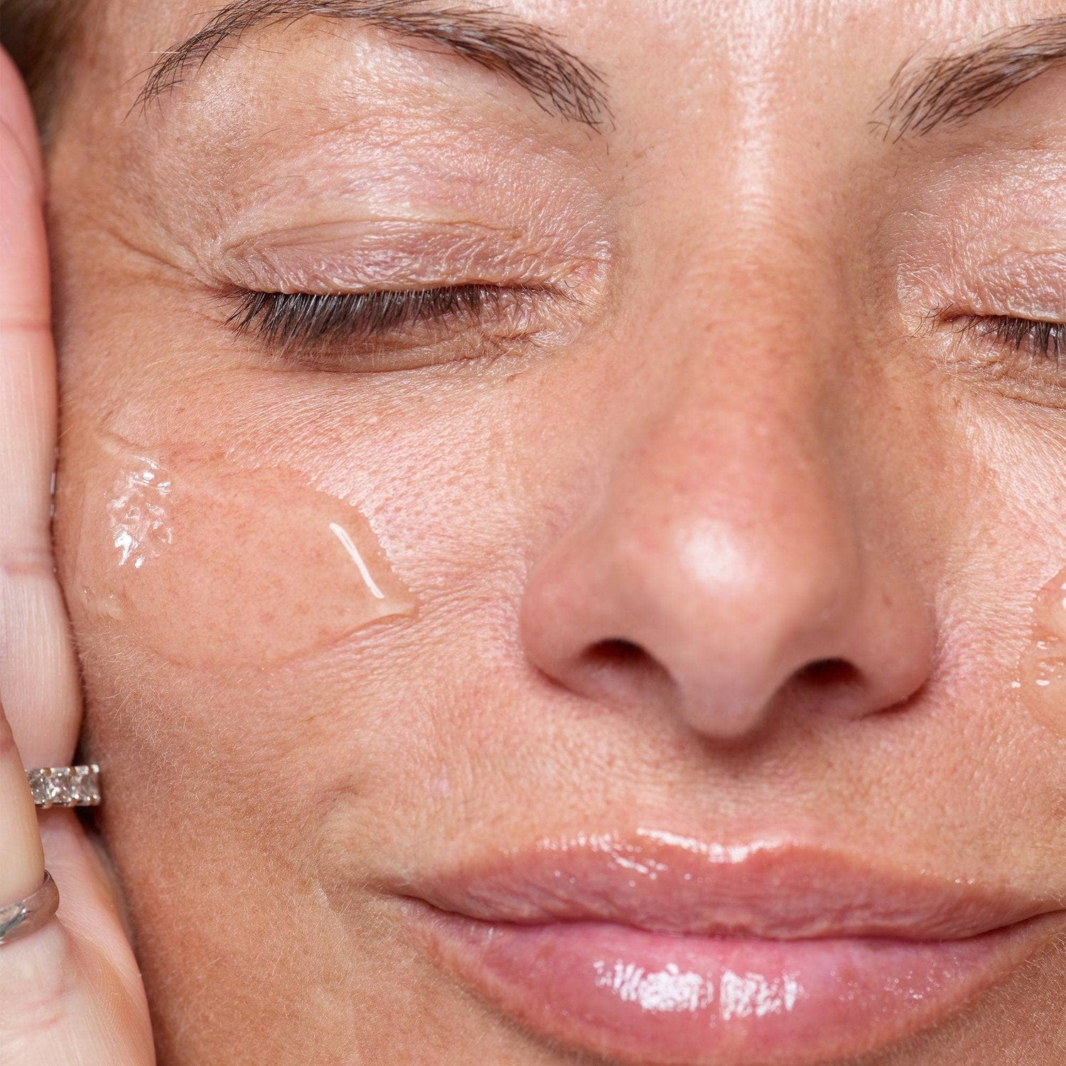 Woman with her eyes closed applying Gentle Hydra-Gel Face Cleanser on her cheek