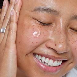 Freckled woman applying Gentle Hydra-Gel Face Cleanser on her cheek