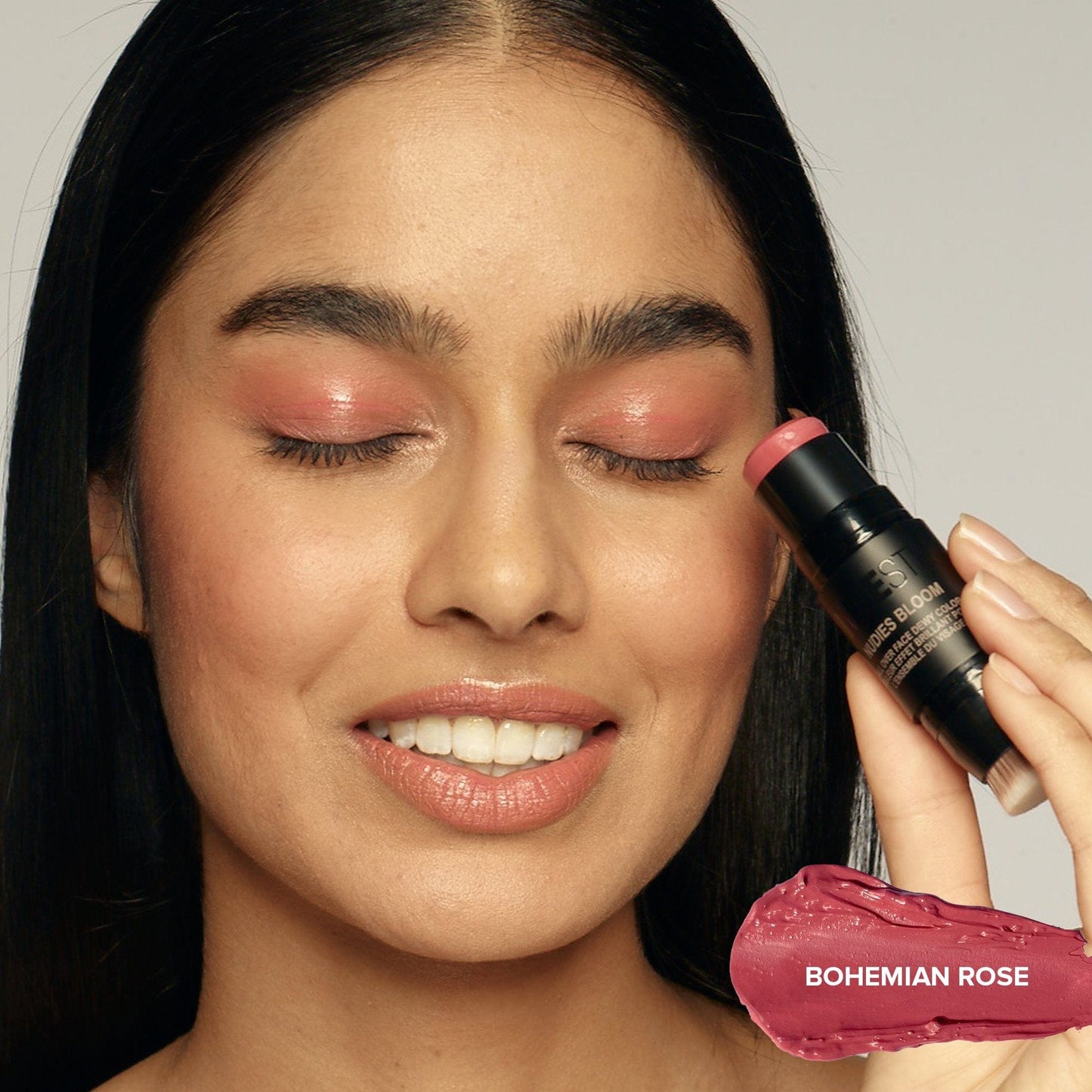 Young woman with her eyes closed applying Nudies Bloom Bohemian Rose on her eyelids