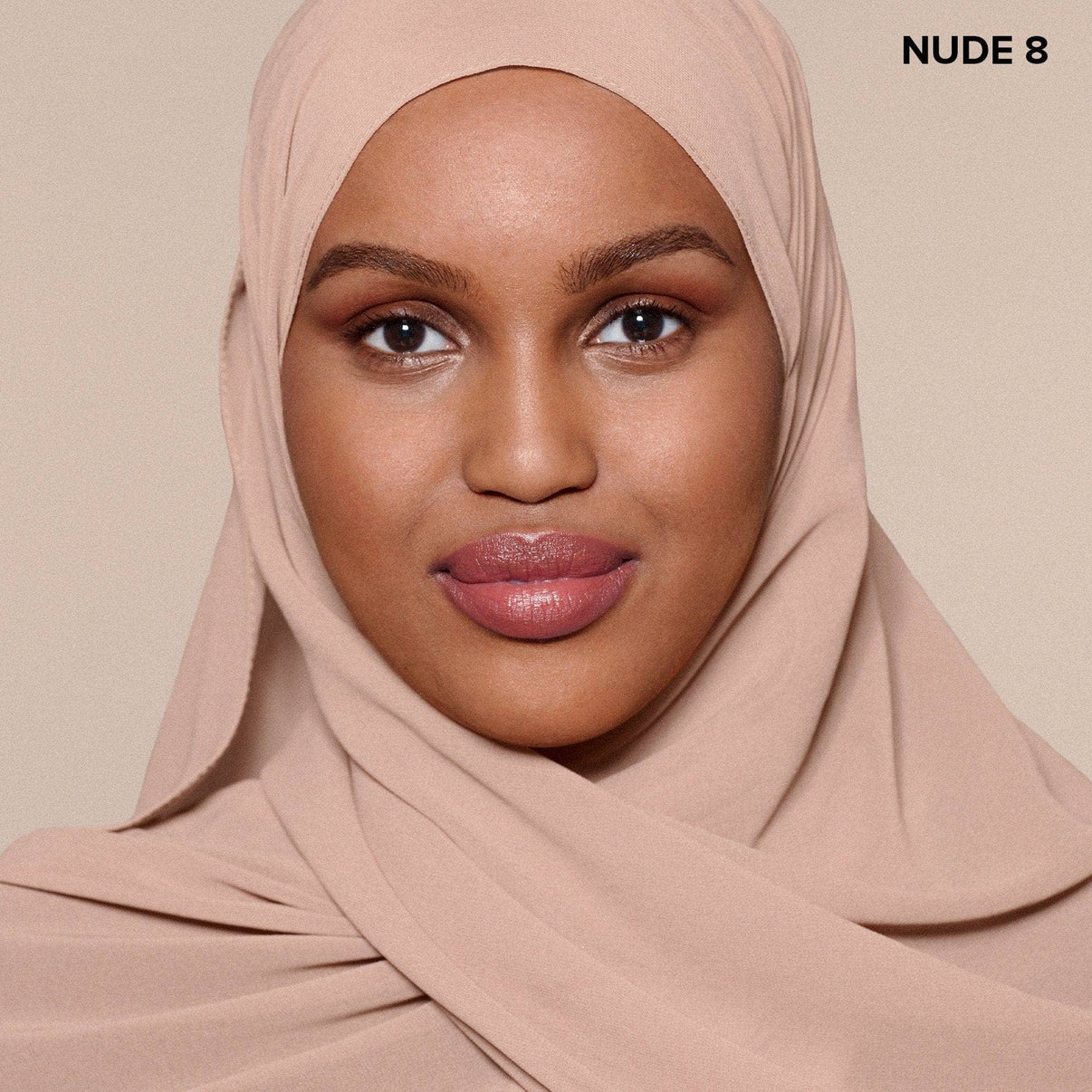 Brown skinned young woman wearing Nudefix cream concealer in shade nude 8
